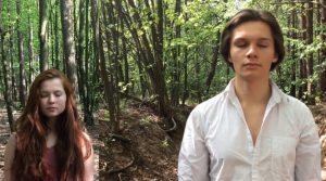 Scena z filmu - dwoje aktorów, dziewczyna i chłopak, stoją na tle lasu z zamkniętymi oczami.